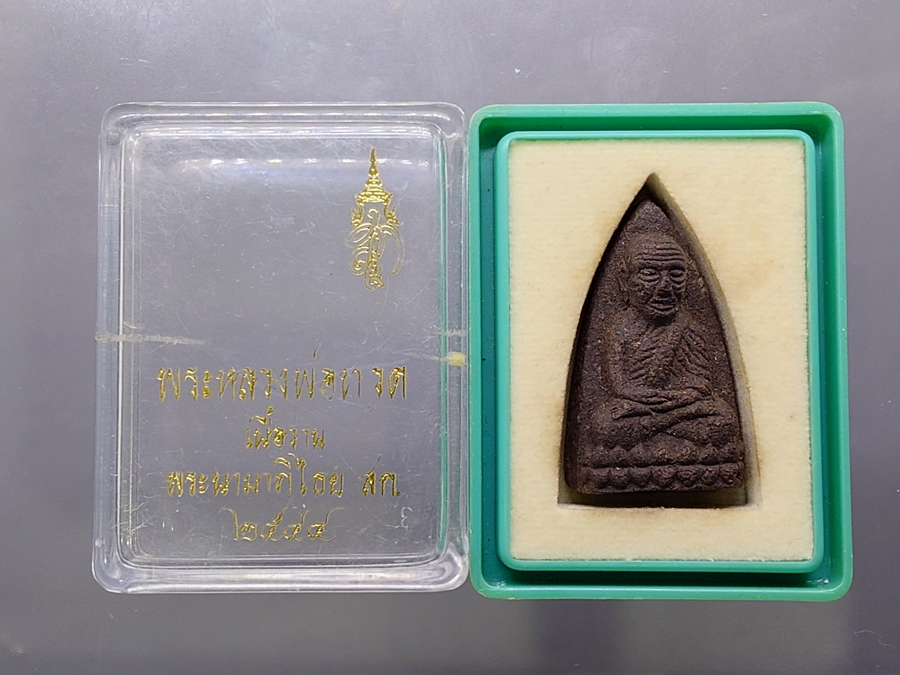 หลวงพ่อทวด พระนามาภิไธย สก. พิมพ์เตารีด เนื้อว่านคลุกรัก วัดห้วยมงคล ปี 2544 พร้อมกล่องเดิม