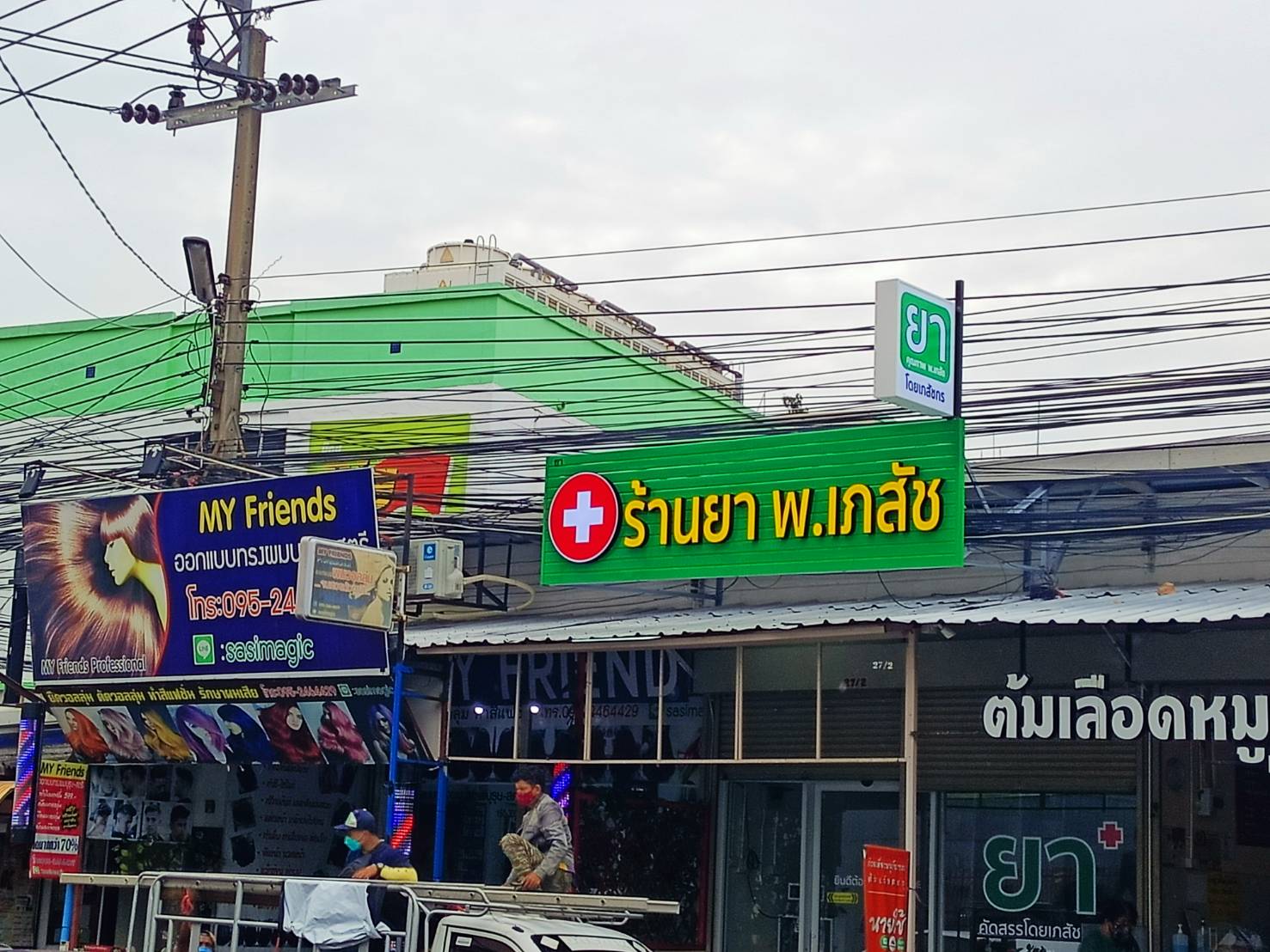 ป้ายตัวอักษรไฟออกหน้า พื้นหลังเป็นแผงตัวซีสีเขียว งานร้านยา พ.เภสัช
