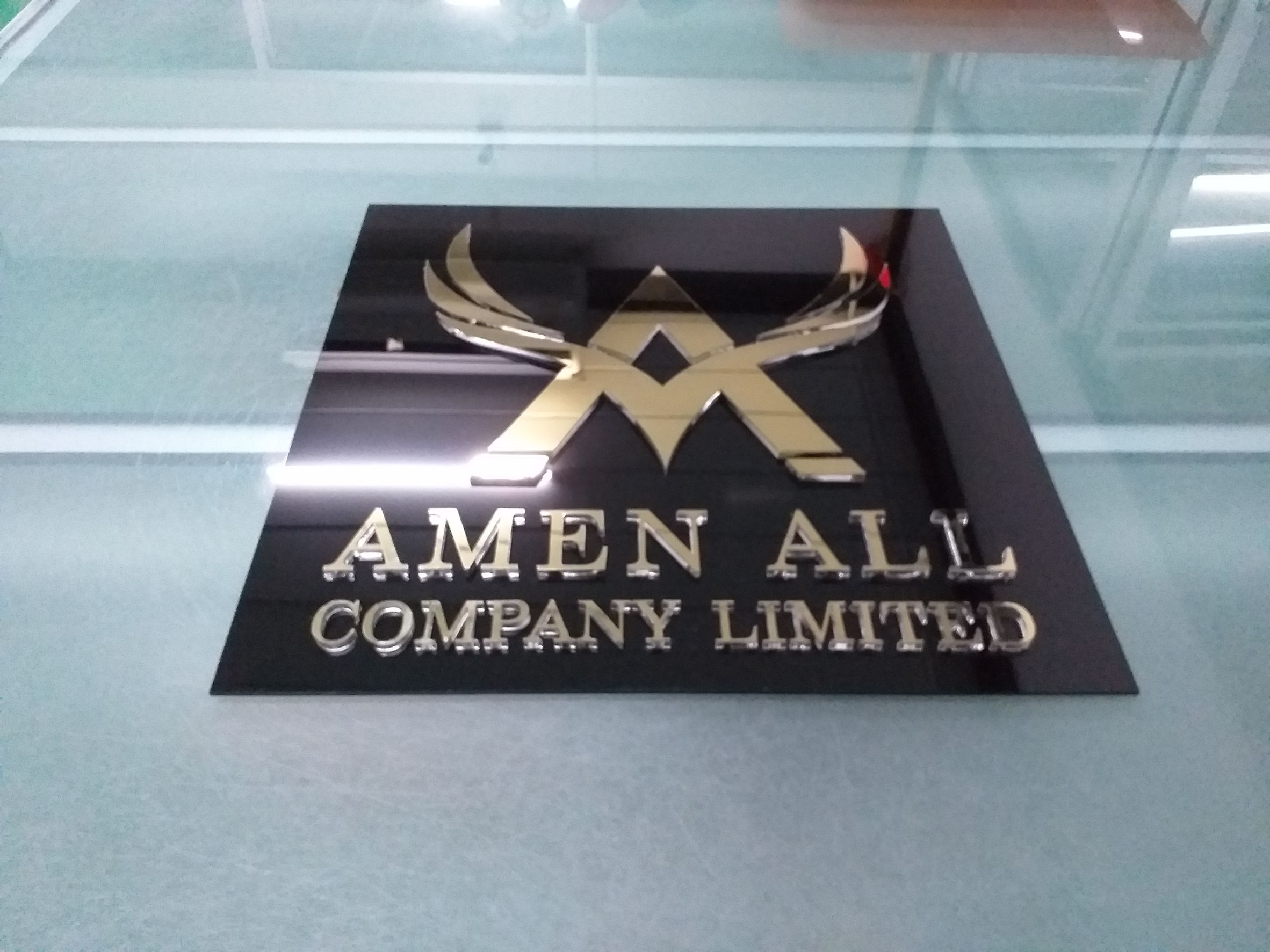 ป้ายเลเซอร์พื้นอะคริลิคไดคัทตัวหนังสือด้านบนติดแผ่นสแตนเลสทองเงา งานAMEN ALL COMPANY