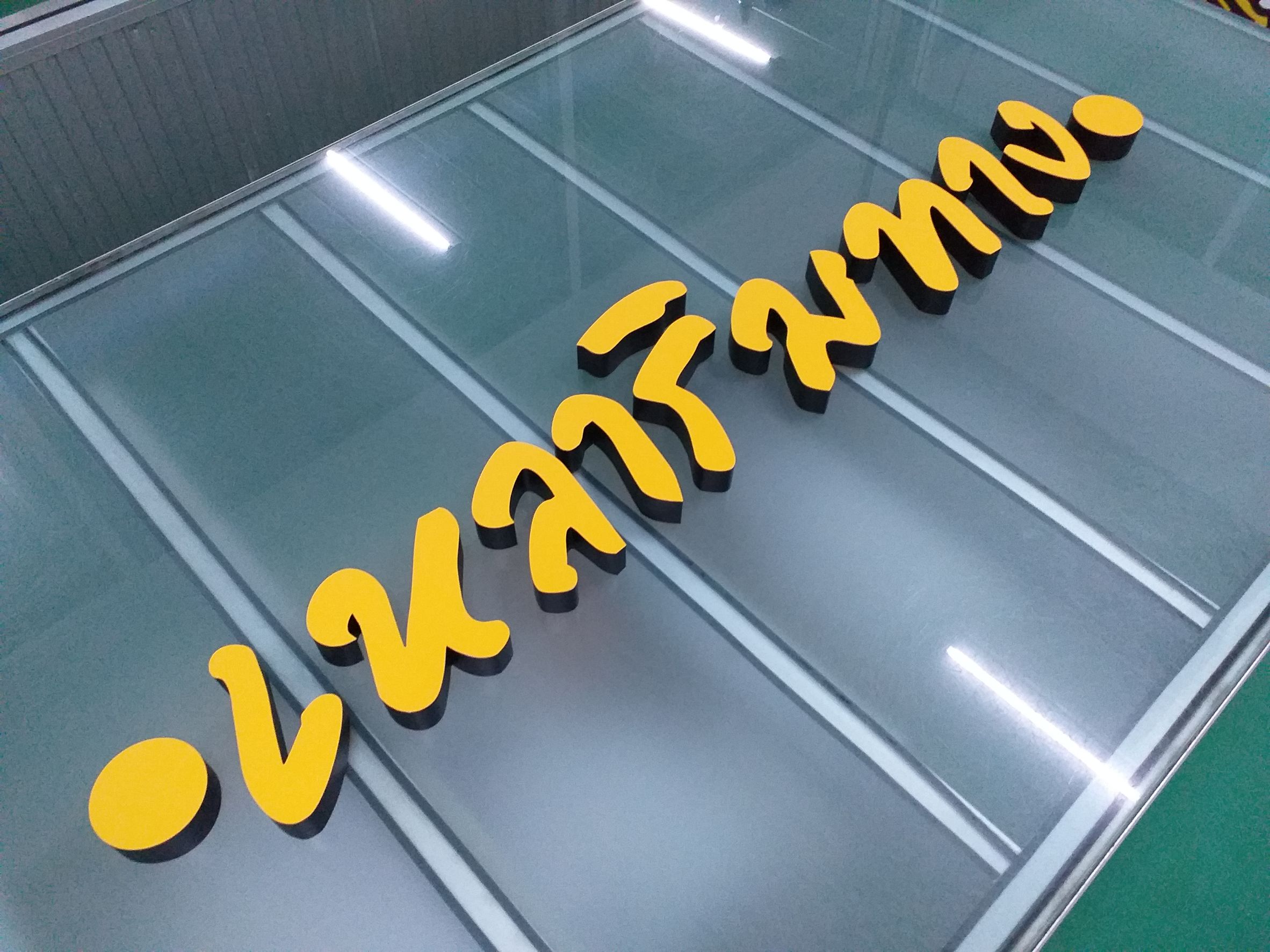 งานปริ้นท์สติกเกอร์โปร่งแสงสีเหลือง ติดลงบนตัวอักษรป้ายไฟ งานเหลาริมทาง