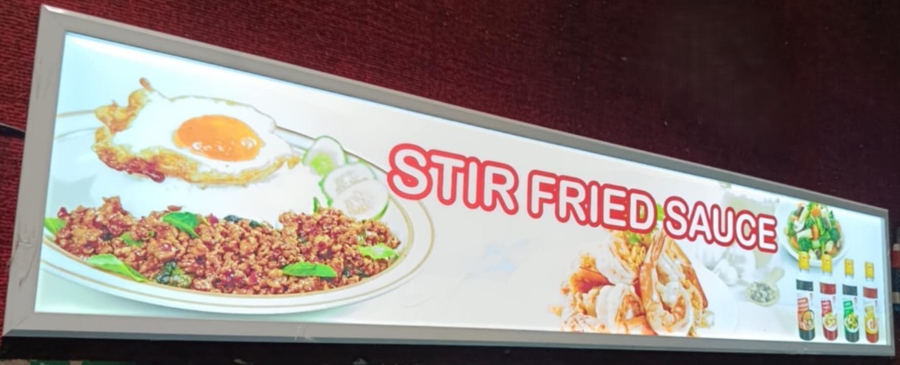ป้ายในภาพเป็นป้ายไฟเมนู Slim Lightbox ของร้านอาหารที่จำหน่ายอาหารผัดซอส (STIR FRIED SAUCE)