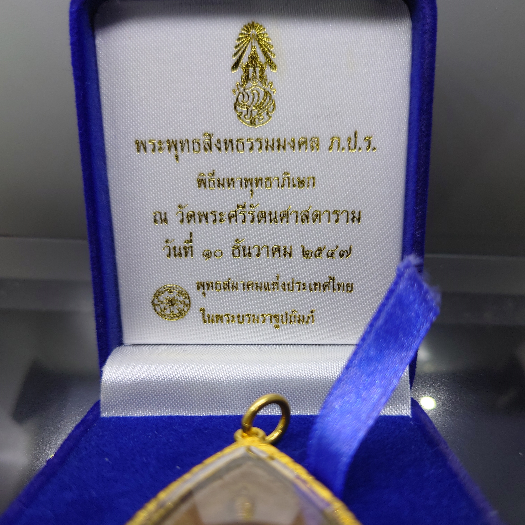 พระพุทธสิงหธรรมมงคล หลังพระปรมาภิไธย ภ.ป.ร.เนื้อนวะ พุทธสมาคมแห่งประเทศไทย ในพระบรมราชูปถัมภ์ พ.ศ.2547 เลี่ยมกรอบทองนพเก้า พร้อมตลับเดิม