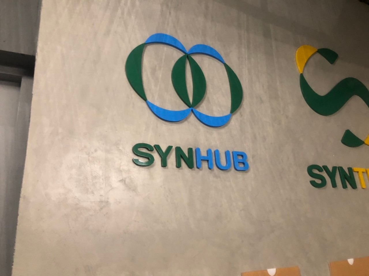 ป้ายชื่อบริษัทและโลโก้ เลเซอร์ฉลุอะคริลิคพ่นสีตามโลโก้ งานSYNTECH SYNHUB CLINITECH