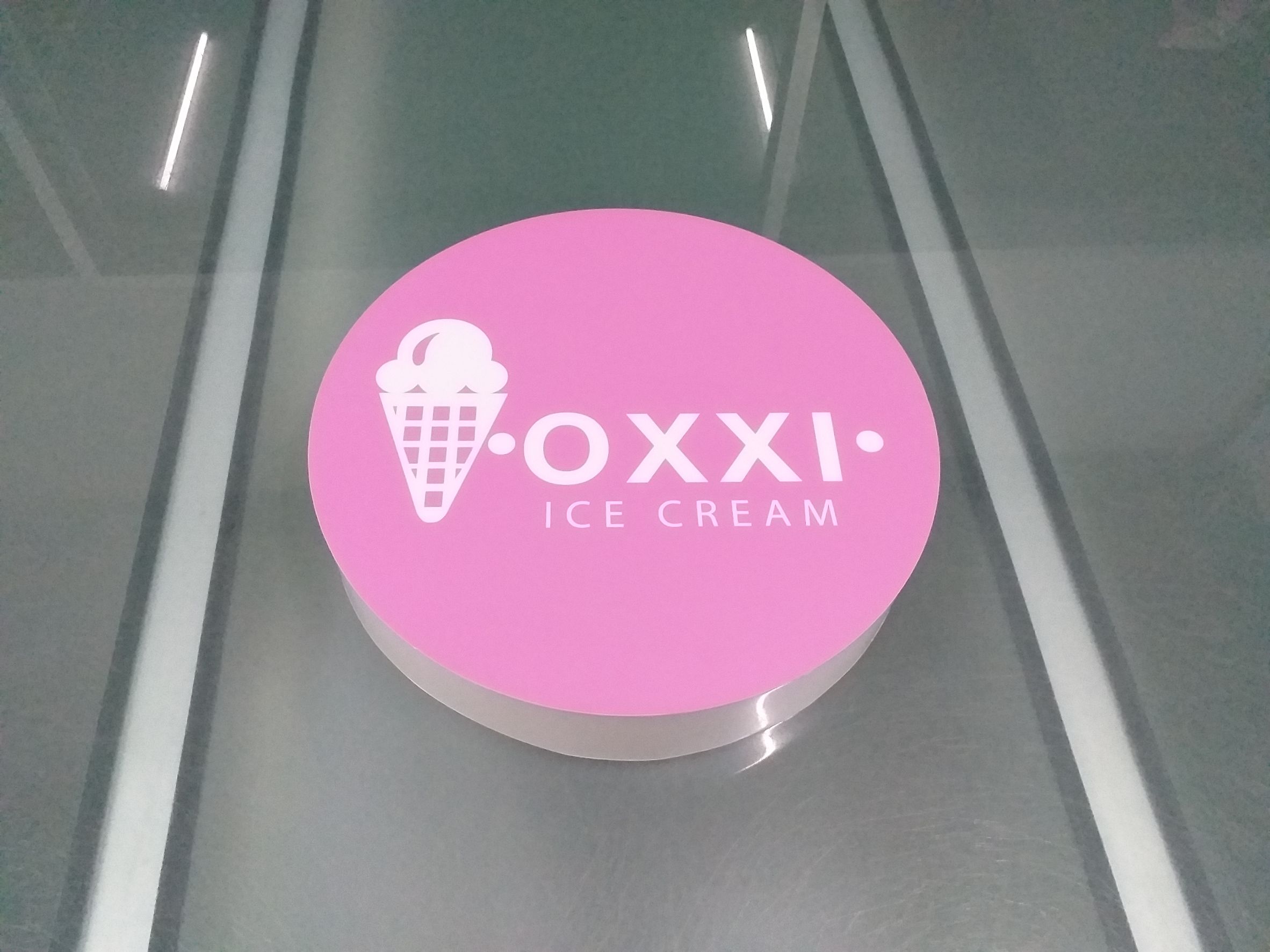 งานพิมพ์สติกเกอร์โปร่งแสงติดลงบนโลโก้กล่องไฟวงกลม งานOXXI ICE CREAM