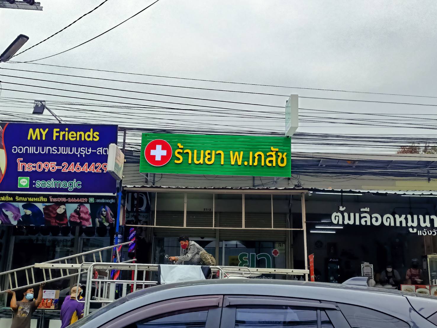 ป้ายตัวอักษรไฟออกหน้า พื้นหลังเป็นแผงตัวซีสีเขียว งานร้านยา พ.เภสัช