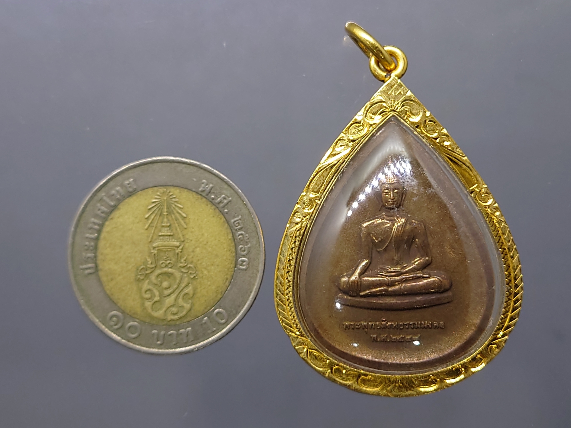 พระพุทธสิงหธรรมมงคล หลังพระปรมาภิไธย ภ.ป.ร.เนื้อนวะ พุทธสมาคมแห่งประเทศไทย ในพระบรมราชูปถัมภ์ พ.ศ.2547 เลี่ยมกรอบทองนพเก้า พร้อมตลับเดิม