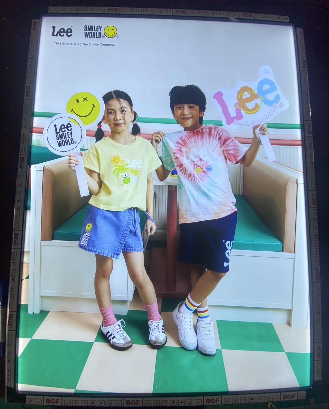 ป้ายในภาพเป็นป้ายไฟโฆษณาเสื้อผ้าเด็กจากแบรนด์ Lee ร่วมกับ Smiley World™