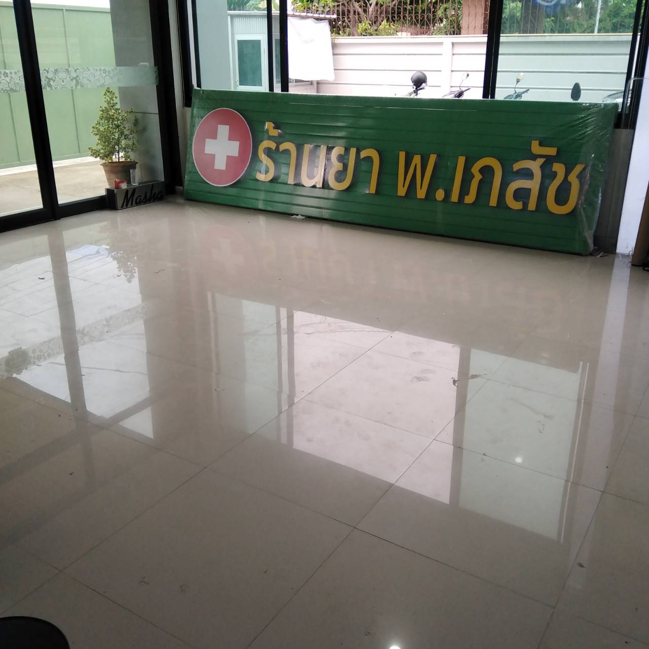 ป้ายตัวอักษรไฟออกหน้า พื้นหลังเป็นแผงตัวซีสีเขียว งานร้านยา พ.เภสัช