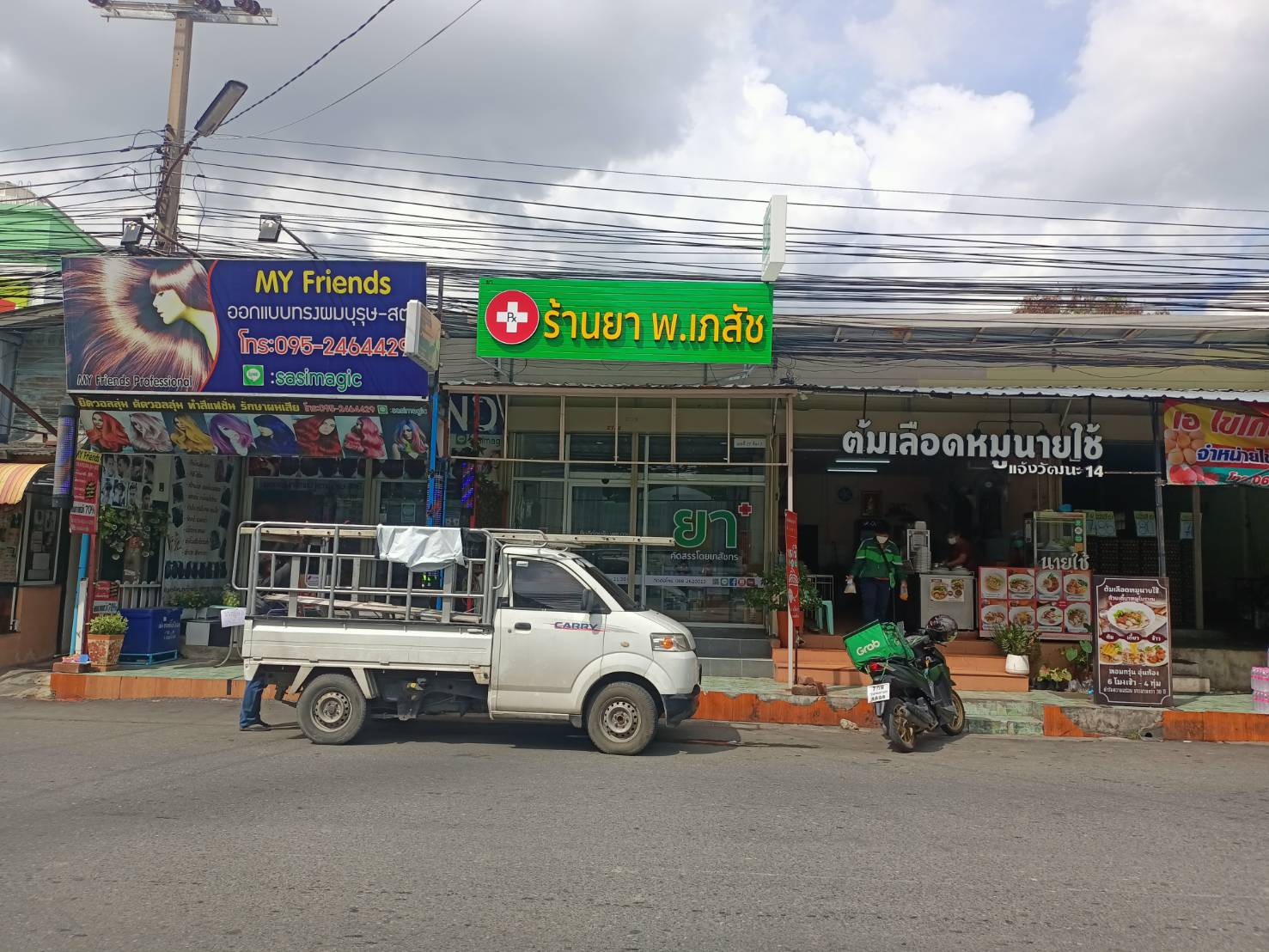 ป้ายตัวอักษรไฟออกหน้า พื้นหลังเป็นแผงตัวซีสีเขียว งานร้านยา พ.เภสัช