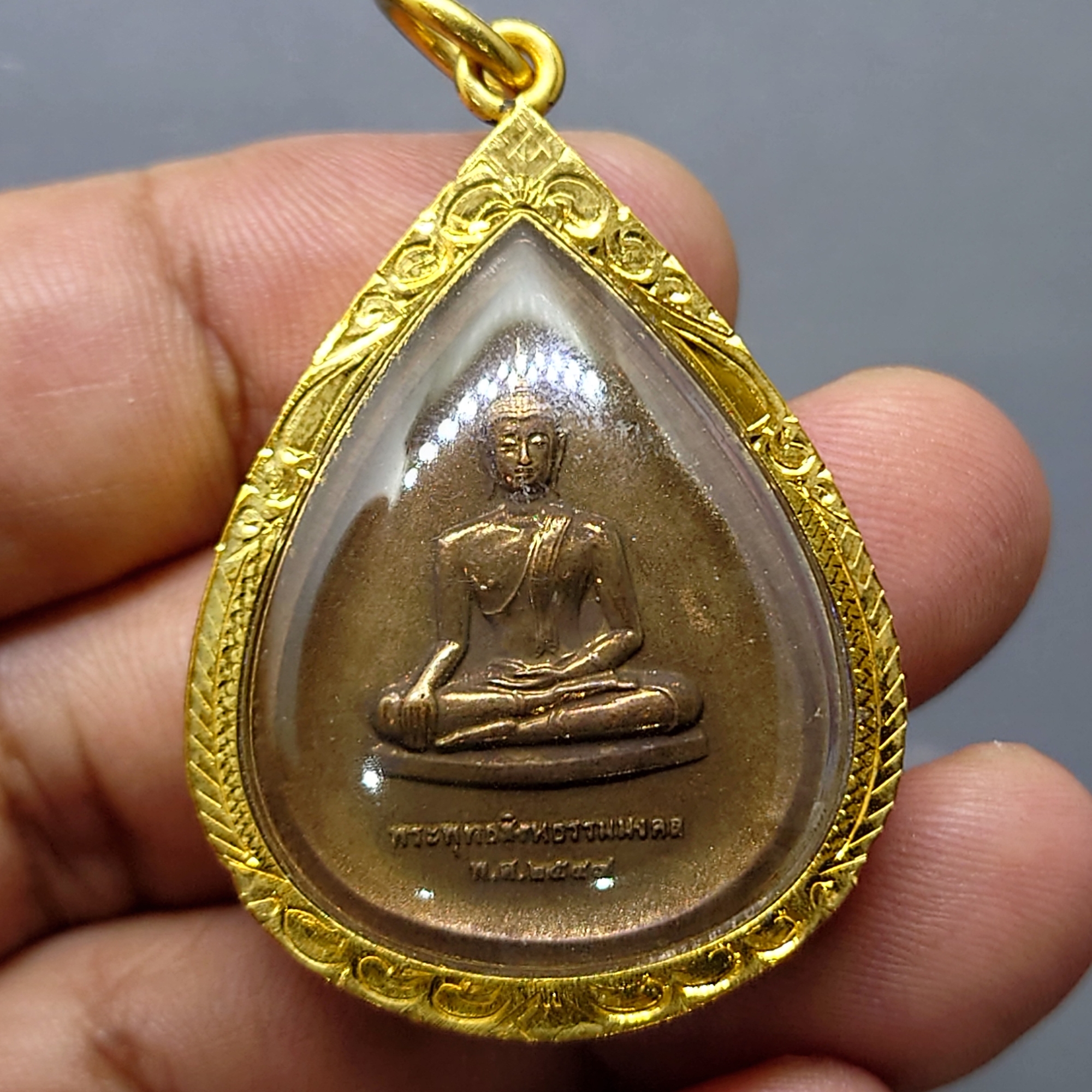 พระพุทธสิงหธรรมมงคล หลังพระปรมาภิไธย ภ.ป.ร.เนื้อนวะ พุทธสมาคมแห่งประเทศไทย ในพระบรมราชูปถัมภ์ พ.ศ.2547 เลี่ยมกรอบทองนพเก้า พร้อมตลับเดิม