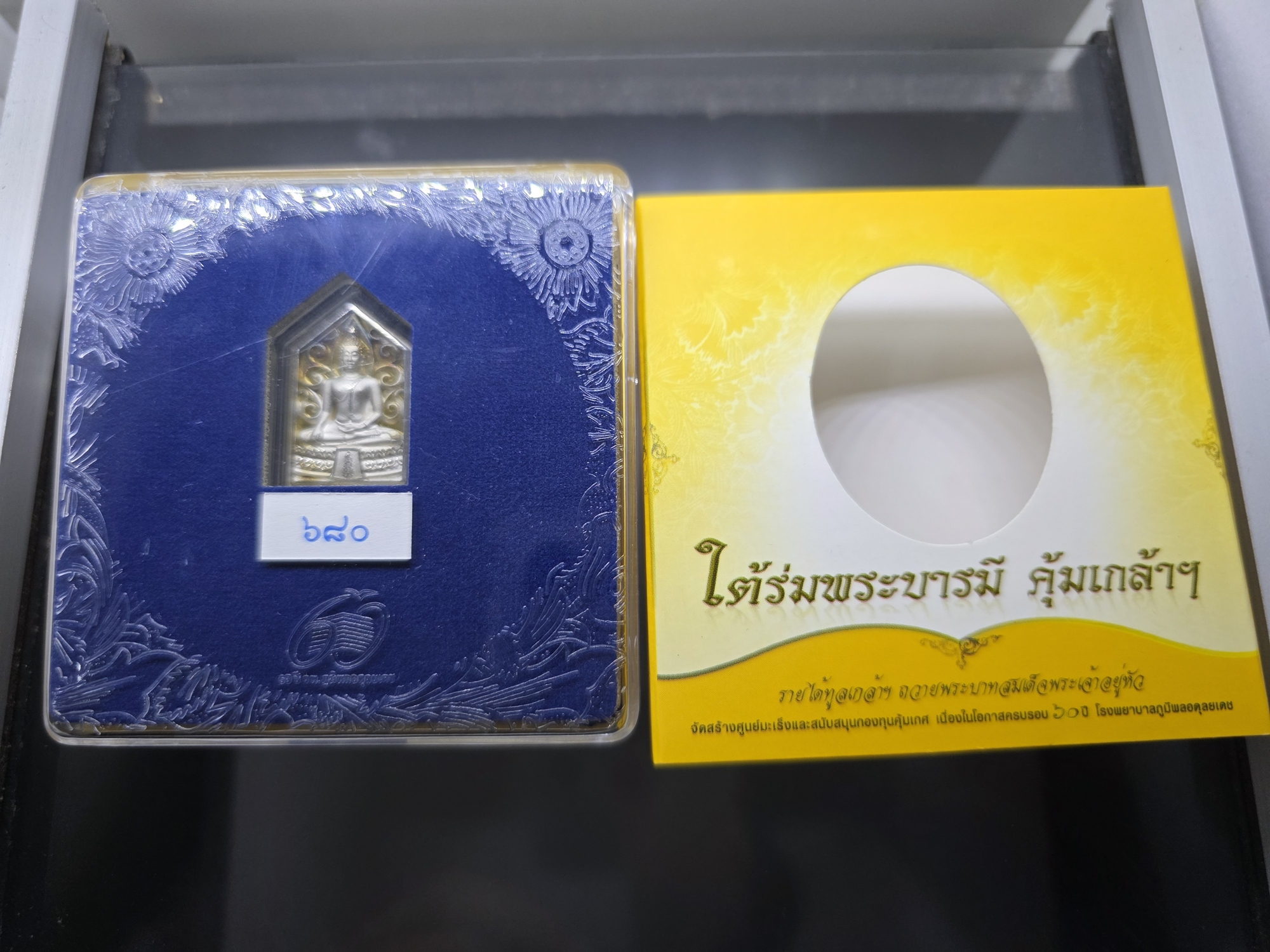 พระพุทธรูปคุ้มเกล้าฯ รูปห้าเหลี่ยม เนื้อเงิน ชุบทองคำขาว "ใต้ร่มพระบารมี คุ้มเกล้าฯ" ที่ระลึก 60 ปี โรงพยาบาลภูมิพลฯ ปี2552 พร้อมตลับเดิม