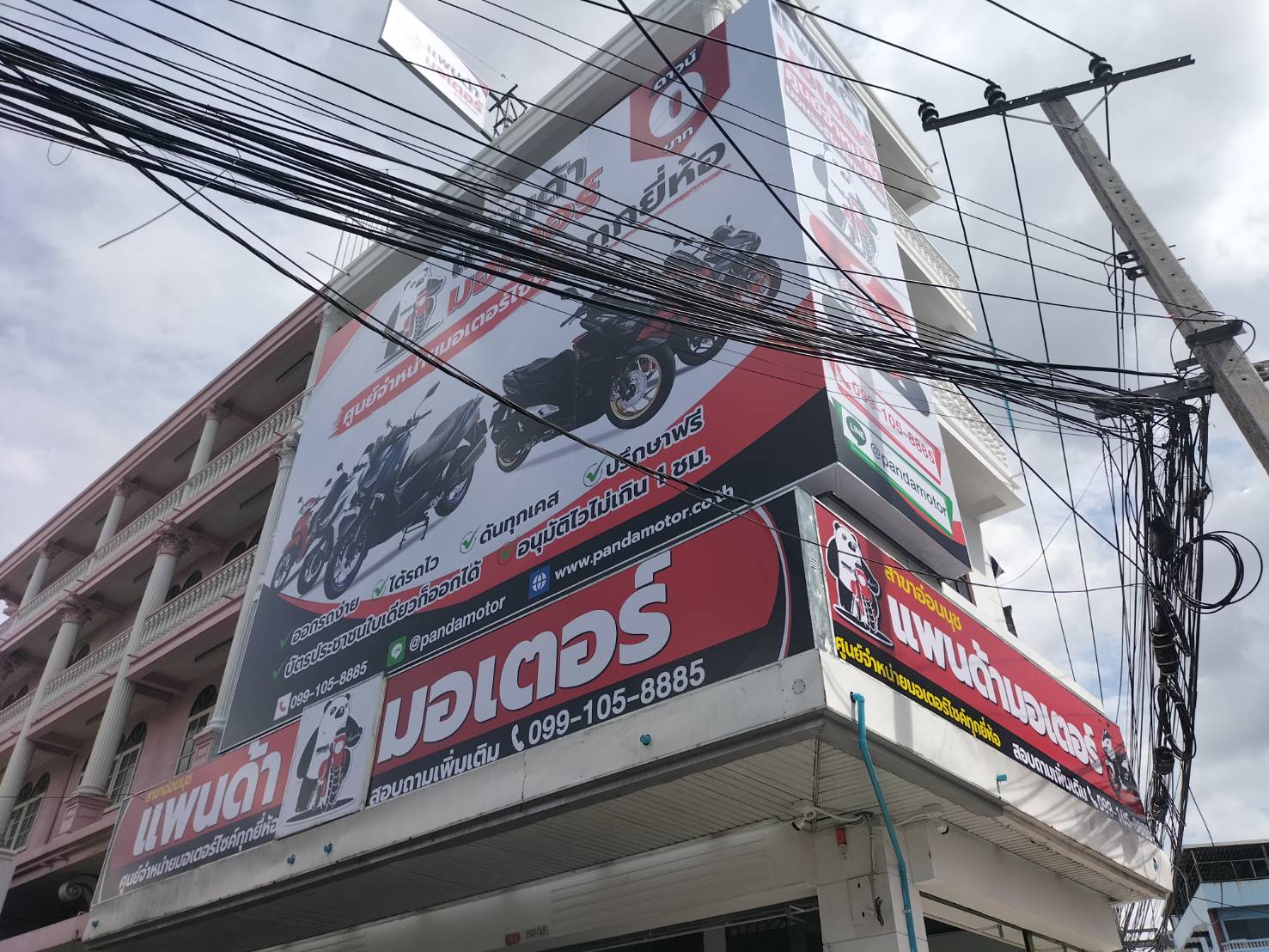 ป้ายไวนิลขึงโครงหน้าตึกงาน แพนด้ามอเตอร์